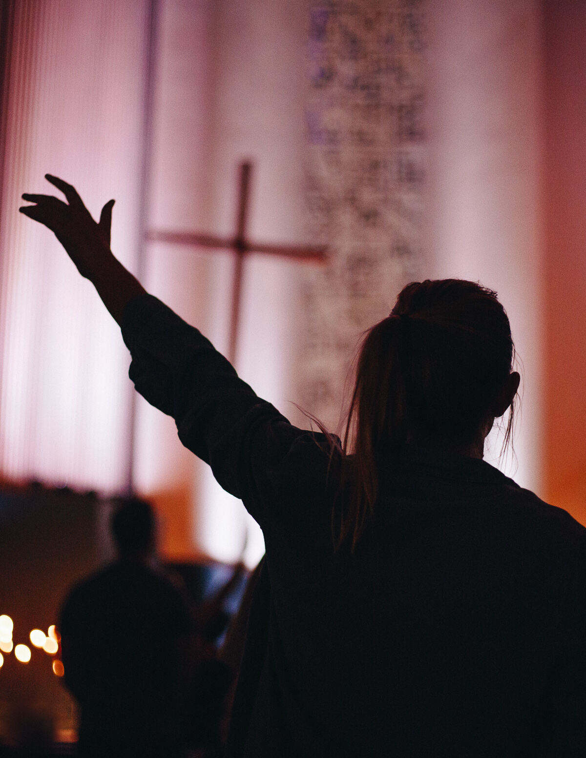 Hand raised against a lit cross